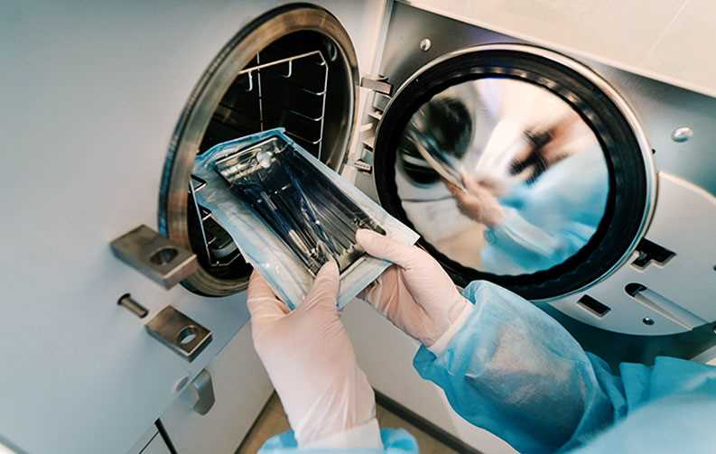 Person putting instruments into autoclave for sterilisation